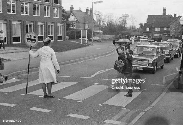 Children from a school in Solihull raise their caps politely to a lollipop lady, UK, 19th November 1972. From a Daily Express series entitled 'The...