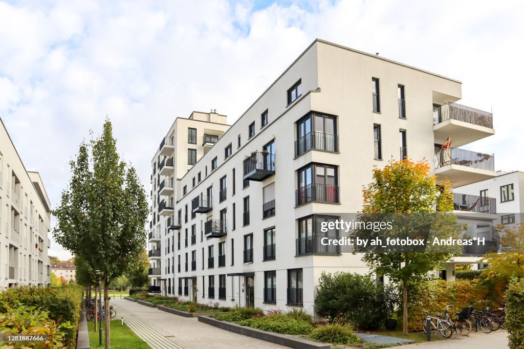 Cityscape with modern residential area, new apartment buildings and green courtyard with pavement and trees in autumn