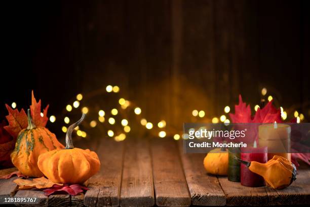 decorazione del ringraziamento con zucche e biglietto d'auguri su sfondo illuminato e un tavolo rustico in legno - candela attrezzatura per illuminazione foto e immagini stock