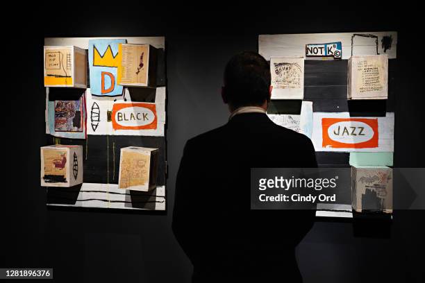 Person stands between Jean-Michel Basquiat's Black and Jean-Michel Basquiat's Jazz during a press preview of the upcoming Contemporary Art Evening...