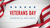 Veterans Day - Honoring All Who Served Poster. Usa veterans day celebration. American national holiday. Invitation template with text and waving us flag on white wooden background
