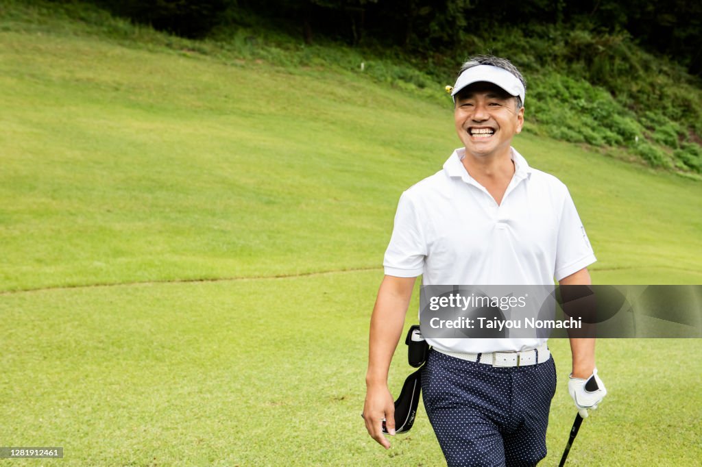 Japanese man walking down the fairway with a smile