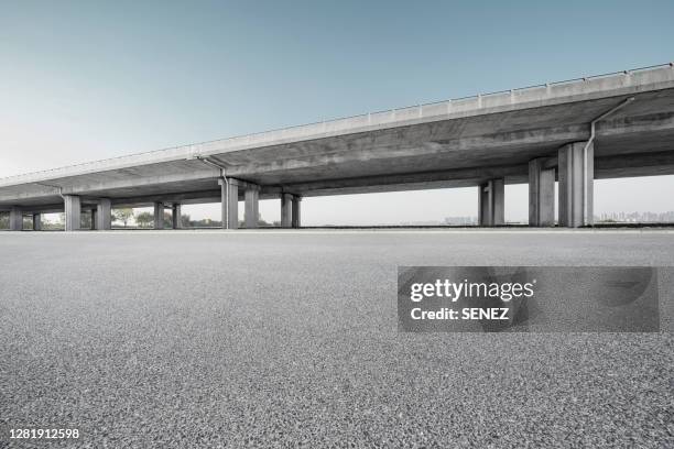 empty pavement under highway bridges - straßenüberführung stock-fotos und bilder