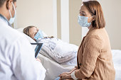 Young woman in protective mask consulting with doctor about her sick friend