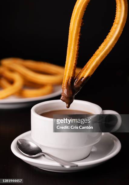 churro being dipped into hot chocolate cup - churros stock pictures, royalty-free photos & images