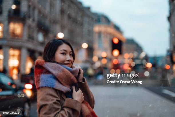 young woman with scarf on the city street - woman snow outside night stock pictures, royalty-free photos & images