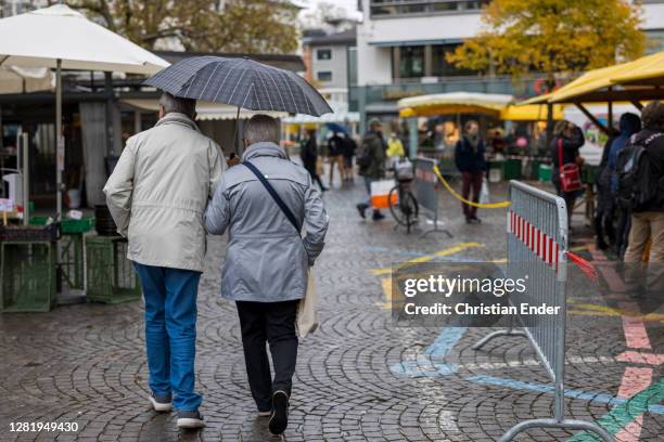 Shoppers, some wearing protective face masks, pass by a market in the city center during the coronavirus pandemic on October 23, 2020 in St. Gallen,...