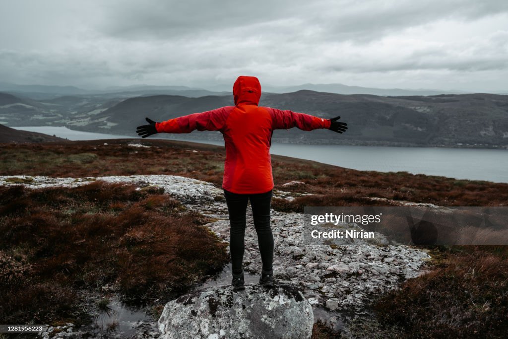 Woman in red jacket with arms outstretched