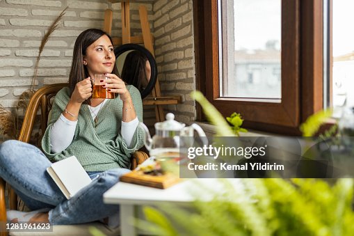 Mujer joven bebiendo su té de invierno y dando la bienvenida a un nuevo día Mujer joven bebiendo su té de invierno y dando la bienvenida a un nuevo día