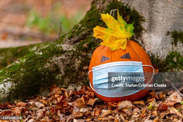 jack o' lantern wearing facial mask. halloween theme. - seasonal sadness stock pictures, royalty-free photos & images