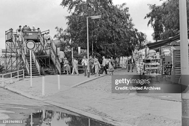 Souvenir shops and refreshment booths need money from the tourists who have a look from a viewing platform to the East, Berlin, Germany 1984.