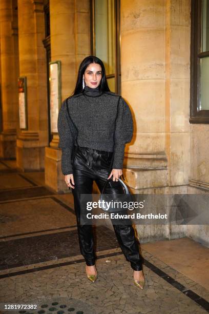 Fiona Zanetti wears long bejeweled earrings, a gray turtleneck oversized wool pullover with puff sleeves, black leather pants, a black leather...