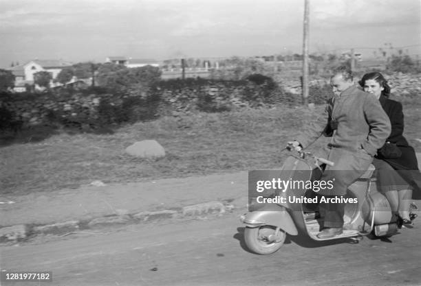 Travel to Rome - Italy in 1950s - couple driving a Vespa on the road Via Appia Antica near Rome. A couple rides a Vespa on the Via Appia Antica near...