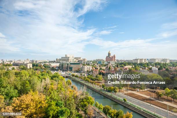 view of trees of a public park, the dâmbovița river, downtown buildings and the colossal romanian palace of parliament (palatul parlamentului) - bucharest stock pictures, royalty-free photos & images