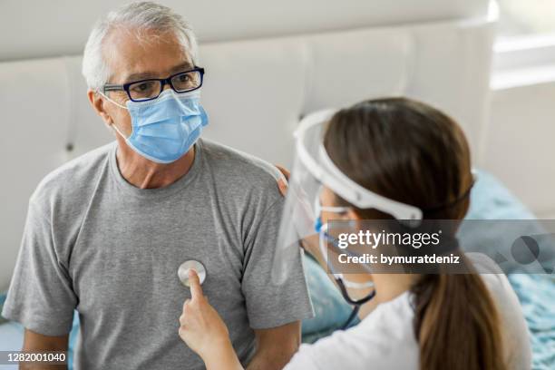 health visitor and a senior man during home visit - emergencies and disasters imagens e fotografias de stock