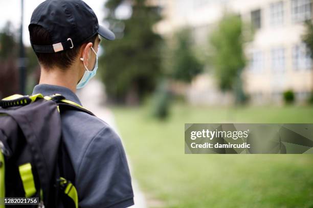 rear view of school teenage boy with face protective mask in front of the school - bullying prevention stock pictures, royalty-free photos & images