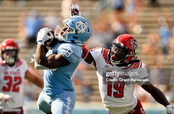 Michael Carter of the North Carolina Tar Heels makes a catch against Joshua Pierre-Louis of the North Carolina State Wolfpack during their game at...