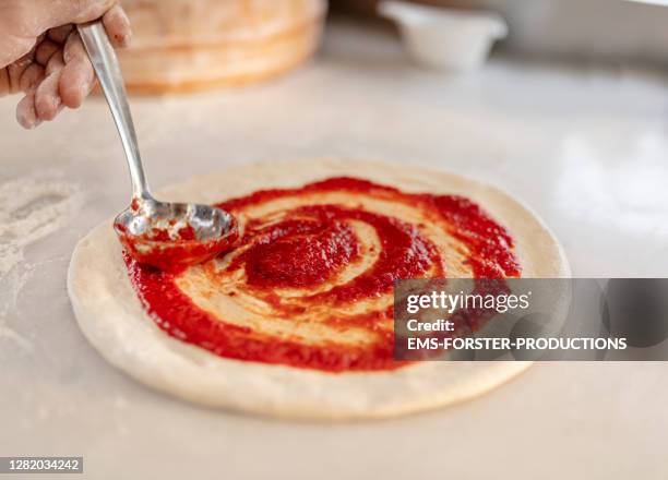 spreading tomato sauce on pizza pan - dough photo stock-fotos und bilder