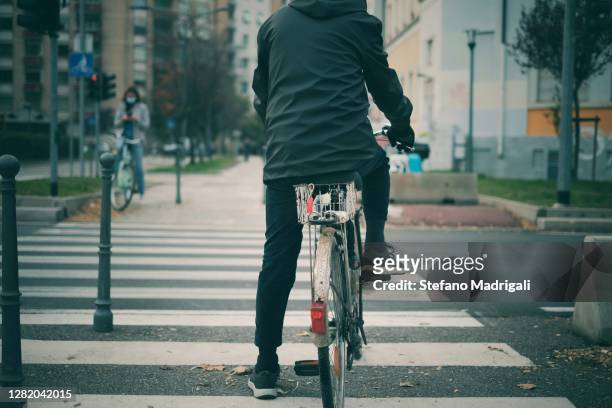 man on bicycle stopped at the traffic lights of a pedestrian crossing in the center, on a main road, concept of sustainable mobility - traffic light empty road stock pictures, royalty-free photos & images