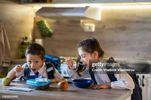 elementary students hurrying eating breakfast before school - children eating breakfast at school stock pictures, royalty-free photos & images