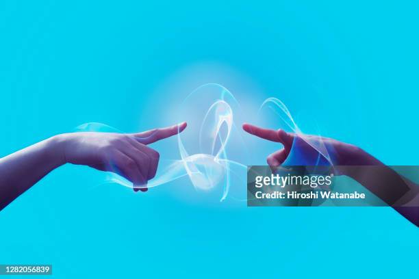 two hands are connecting with light trails - innovation stock-fotos und bilder