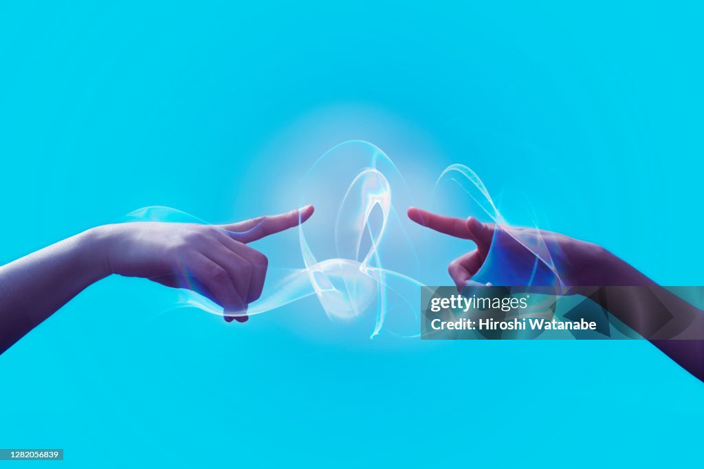 Two hands are connecting with light trails