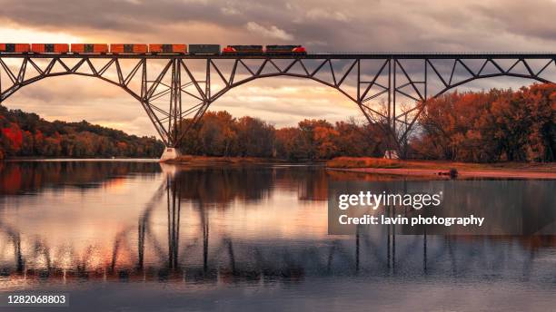 autumn train moving across a bridge with reflections - minnesota stock pictures, royalty-free photos & images