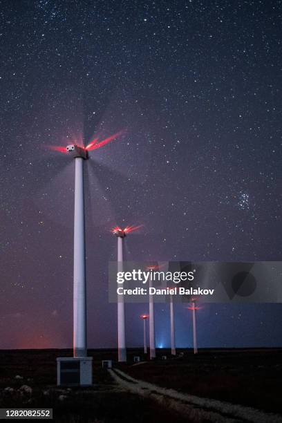 renewable energy systems. wind turbine power station park at night, working under the starry sky and the milky way. blurred motion. - social impact stock pictures, royalty-free photos & images