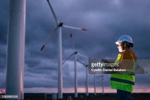 renewable energy systems. electricity maintenance engineer working on the field at a wind turbine power station at dusk with a moody sky behind. blurred motion. - engineer stock pictures, royalty-free photos & images