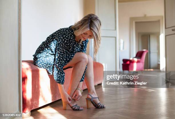 beautiful mature woman putting on shoes - vestir se fotografías e imágenes de stock