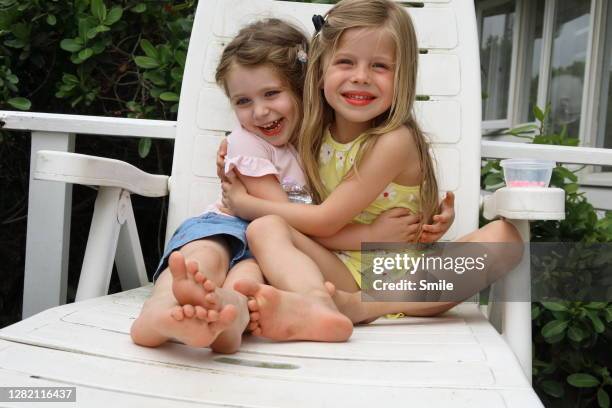 two beautiful young girls embracing on pool lounger - 2 peas in a pod stock pictures, royalty-free photos & images