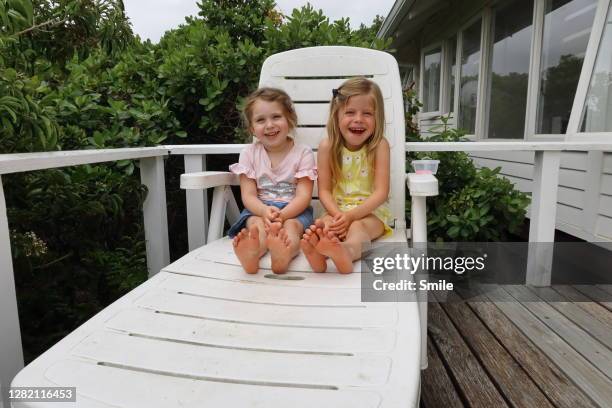 two beautiful and happy young girls sitting on pool lounger - 2 peas in a pod stock pictures, royalty-free photos & images