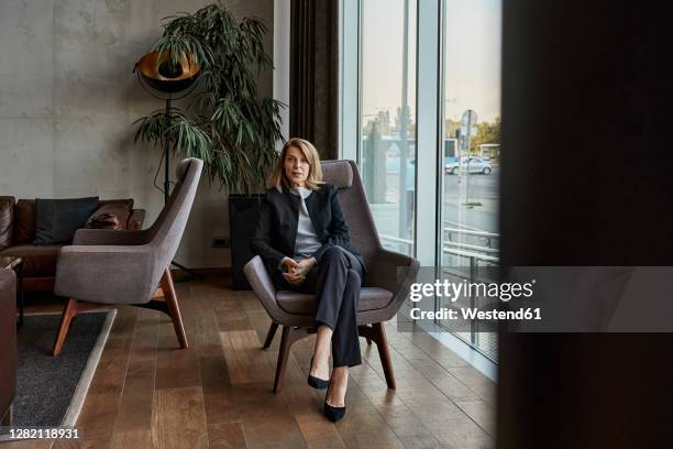serious senior woman sitting on chair in hotel lobby - lounge chair bildbanksfoton och bilder