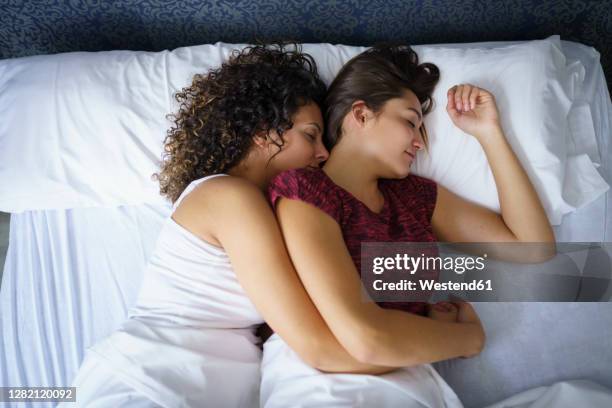 lesbian couple sleeping on bed at home - lesbian bed stock pictures, royalty-free photos & images