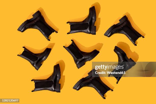 studio shot of black leather boots against yellow background - black boot stock pictures, royalty-free photos & images