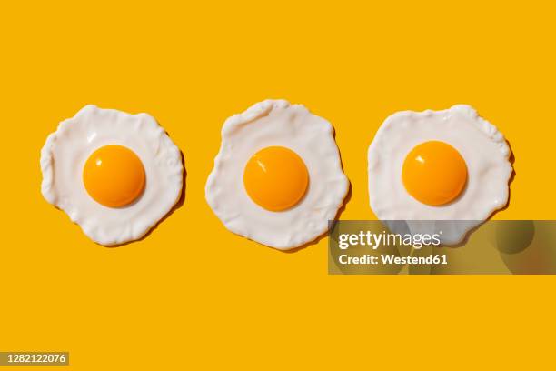 studio shot of three fried eggs - food on coloured background stock pictures, royalty-free photos & images