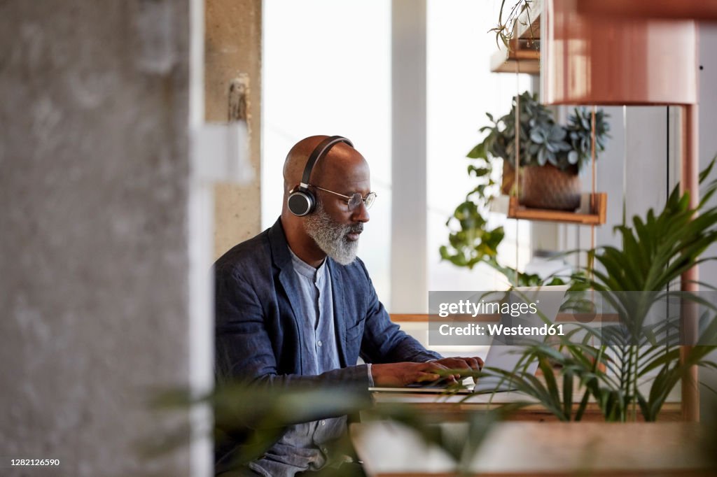 Mature male freelancer using laptop while sitting at table and working from home