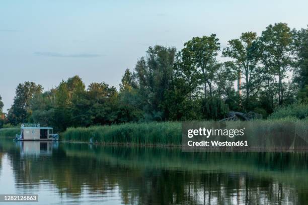 scenic view of nature and houseboat in lake during sunset - hausboot stock-fotos und bilder