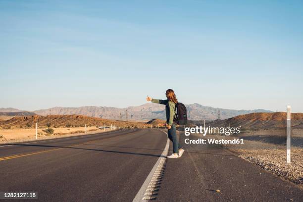 woman hitchhiking on desert road, nevada, usa - autostop fotografías e imágenes de stock