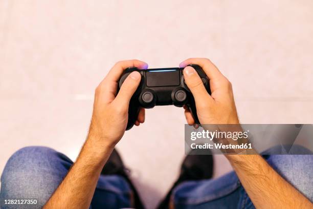 young male gamer holding controller while playing at home - control pants foto e immagini stock