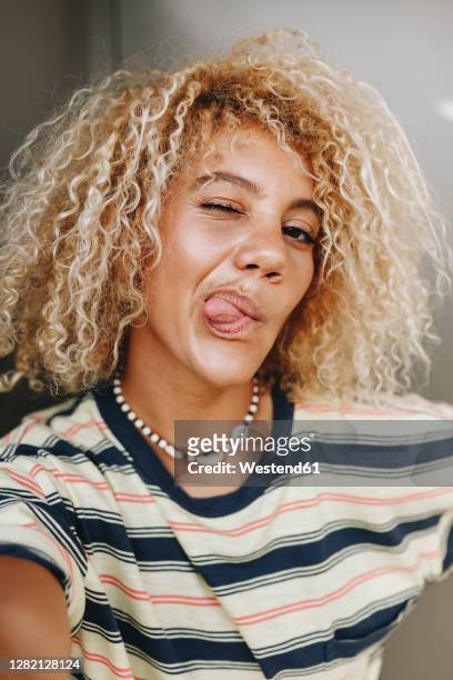 woman with blond curly hair taking selfie while sticking out tongue - blonde woman selfie stock pictures, royalty-free photos & images