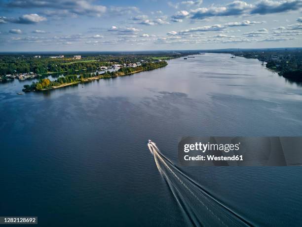 boat leaving wake on volga river against sky - volga stock-fotos und bilder