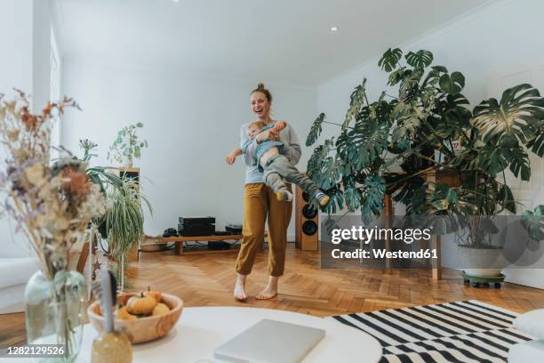 mother playing with boy while standing at home - family livingroom stock-fotos und bilder