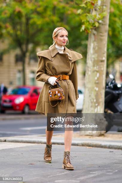 Leonie Hanne wears a brown headband, a khaki trench coat / dress with shoulder pads, an orange belt, a brown Chloe bag, a white wool turtleneck...