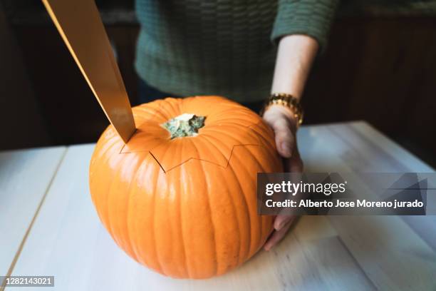 close-up woman's hands carving a pumpkin for halloween night - schnitzen stock-fotos und bilder