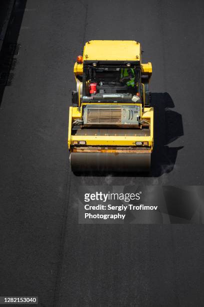 road construction with roller compacting new asphalt - tejer stock-fotos und bilder