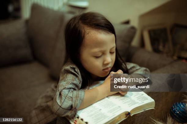 kid reading the holy bible and praying - trust god stock pictures, royalty-free photos & images