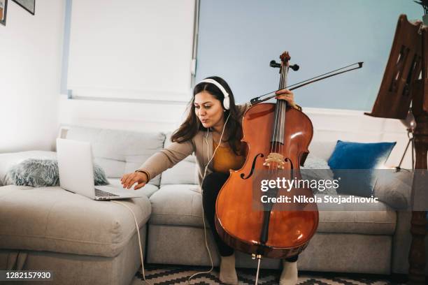 smiling girl playing a cello at home - girl cello stock pictures, royalty-free photos & images