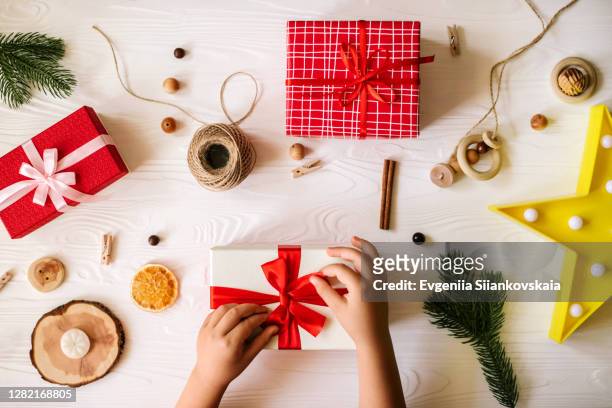 child's hands tying a bow on a gift box on christmas background. - lint strik stockfoto's en -beelden
