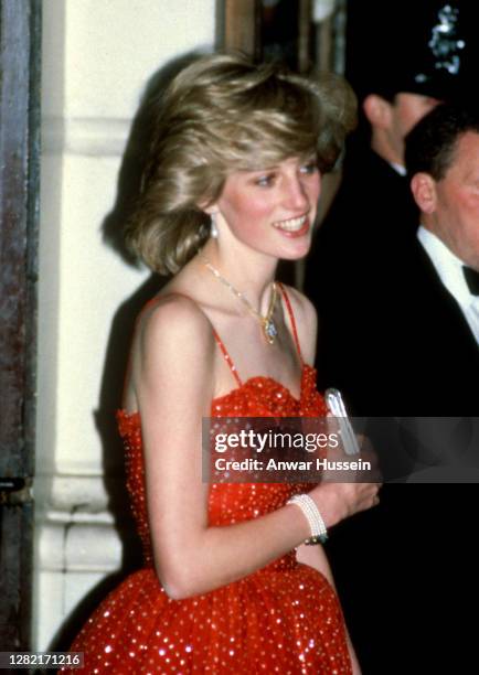 Diana, Princess of Wales, wearing a red and gold spangled chiffon gown designed by Bellville Sassoon and a gold and diamond necklace in the shape of...